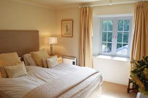 a bedroom with a large white bed and a window at Mews Cottage in Cury