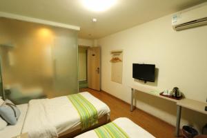 ein Hotelzimmer mit 2 Betten und einem Flachbild-TV in der Unterkunft Pai Hotel Jiuquan Jianshe Road Ouzhou Yuan in Jiuquan