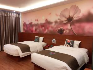 2 Betten in einem Zimmer mit einem Blumengemälde an der Wand in der Unterkunft PaI Hotel Zhengzhou Jingsan Road Fortune Plaza in Zhengzhou