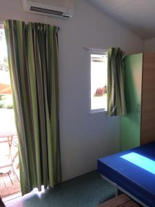 um quarto com cortinas verdes e uma janela em Parque de Campismo Orbitur Valado na Nazaré
