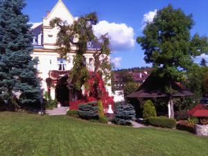 a large white house with flowers in the yard at Willa Sanssouci in Kudowa-Zdrój