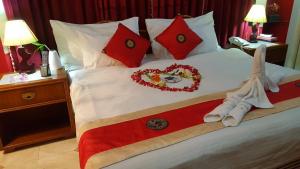 Una cama con almohadas rojas y adornos. en Babylon Hotel & Serviced Apartment, en Dhaka