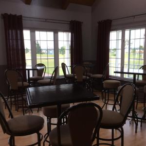 a dining room with tables and chairs and windows at Villegiature Deux Rivieres Resort in Tracadie