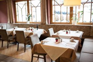 ein Restaurant mit weißen Tischen, Stühlen und Fenstern in der Unterkunft Hotel Das Zentrum in Sölden