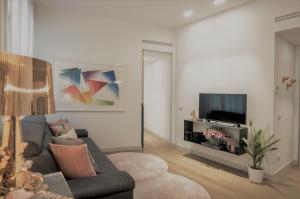 ein Wohnzimmer mit einem Sofa und einem TV in der Unterkunft Madeleine apartments - Brera in Mailand