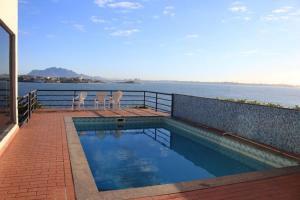 a swimming pool with two chairs next to the water at Hospedagem Praia da Costa in Vila Velha