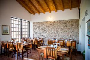 a restaurant with wooden tables and chairs and a stone wall at Agriturismo Bosco Del Gal in Castelnuovo del Garda