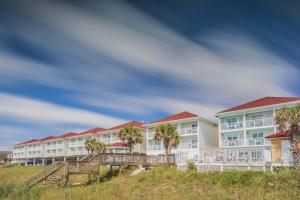 a row of hotels on the beach with palm trees at The Islander Inn in Ocean Isle Beach