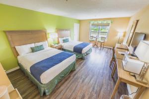 a hotel room with two beds and a television at The Islander Inn in Ocean Isle Beach