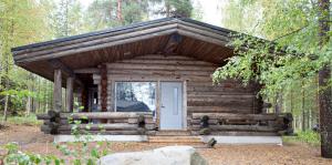 een blokhut met een deur in het bos bij Holiday Club Pyhäniemi Cottages in Kihniö