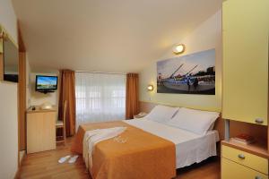 リミニにあるHotel Capriのベッドとテレビが備わるホテルルームです。