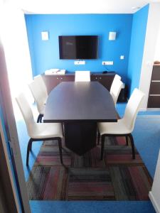 ein Esszimmer mit einem schwarzen Tisch und weißen Stühlen in der Unterkunft Hotel de la Seine in La Frenaye