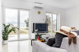 a white living room with a couch and a tv at Holiday home Nora in Drače