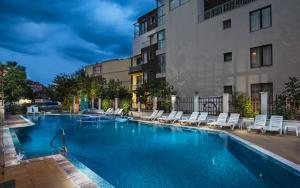 a large swimming pool with chairs and a building at Flagman Hotel in Sozopol