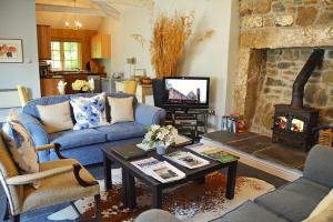 a living room with a blue couch and a fireplace at Spring Water Barn in Helston
