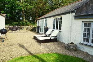 a patio with a bench and a grill in a yard at Spring Water Barn in Helston