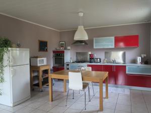 uma cozinha com uma mesa de madeira e um frigorífico branco em Kerhervé em Cléden-Poher