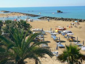 a beach with a bunch of people and the ocean at Central Palace Malfà in Scoglitti