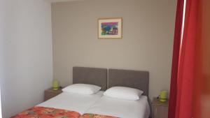 een bed met twee witte kussens en een foto aan de muur bij Amadria Park Camping Trogir - Apartments in Seget Vranjica