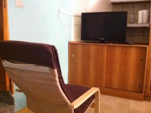een woonkamer met een stoel en een televisie bij Sa Domo Antiga in Osilo