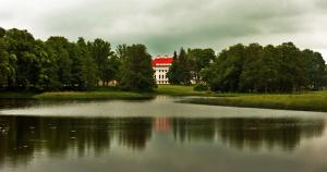 a large white house sitting on top of a lake at Pakruojis Manor's Palace Boutique Hotel in Pakruojis