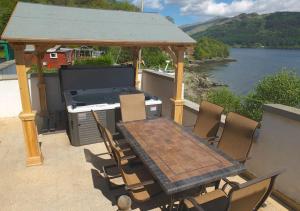 a wooden table and chairs on a patio with a gazebo at Jenny's Bay at Loch Goil in Lochgoilhead