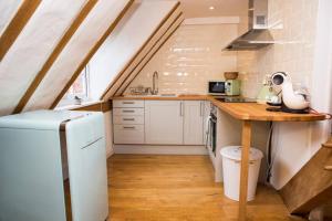 cocina con armarios blancos y encimera de madera en The Apartment Stratford Upon Avon - Town Centre, en Stratford-upon-Avon