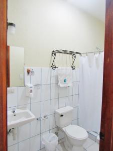 a white bathroom with a toilet and a sink at Hotel Palmeras de Elim in Matagalpa