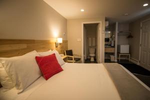 sypialnia z dużym białym łóżkiem z czerwoną poduszką w obiekcie Motel Colonial w mieście Rimouski