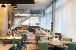 un restaurante con mesas y sillas y una escalera en Leonardo Hotel London Watford en Watford