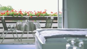 a room with a table and chairs and a balcony with flowers at Hotel zur Bever in Telgte