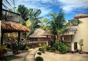 a resort with palm trees and a wooden walkway at Caribbean Beach Cabanas - A PUR Hotel in Placencia Village