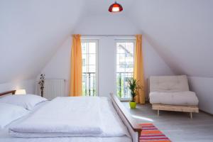 een witte slaapkamer met een bed en een stoel bij Apartment Schiller 3 in Braşov