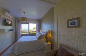 um quarto com uma cama branca e uma janela em Morada da Lagoa na Praia do Rosa