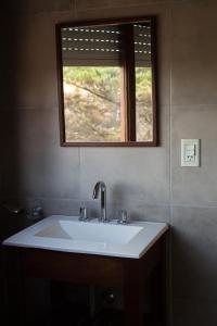 lavabo con espejo y ventana en Hotel Alfa, en Villa Gesell