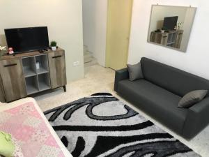 a living room with a black couch and a television at Cempaka Homestay Batu Pahat in Batu Pahat