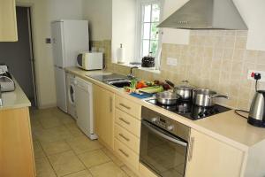 cocina con fregadero y fogones horno superior en St Corantyn Cottage, en Helston