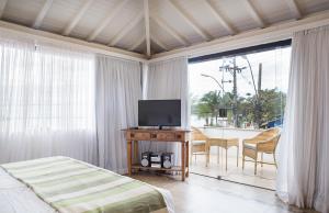 1 dormitorio con 1 cama y 1 mesa con TV en Passeio das Palmeiras en Búzios