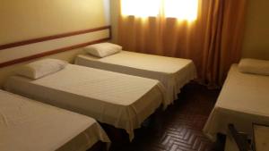 a hotel room with two beds and a window at Hotel Nacional Montes Claros in Montes Claros