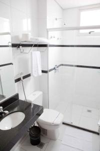 a white bathroom with a toilet and a sink at Serras Hotel in Cuiabá