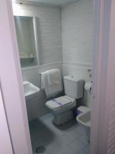 a white bathroom with a toilet and a sink at Hotel Montesol Arttyco in Sierra Nevada