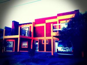 a red building with a car parked in front of it at Departamentos Las Grutas Enjoy in Las Grutas