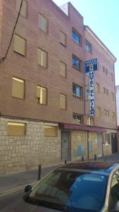 un edificio de ladrillo con un cartel delante en Hostal Juanito, en Móstoles