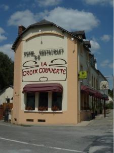 Um edifício castanho com um cartaz de cooperativa. em Logis Hôtel-Restaurant La Croix Couverte em Mayenne