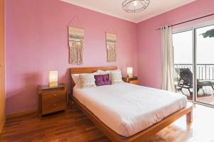 カニコにあるReis Magos II by An Island Apartのピンクの壁のベッドルーム1室、ベッド1台(ランプ2つ付)