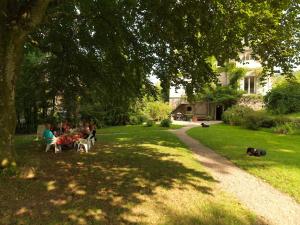 personnes assises à des tables dans un parc sous un arbre dans l'établissement Chateau du Pont Jean, à Fresse-sur-Moselle