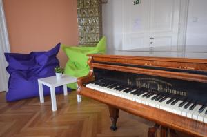 - un piano dans le salon avec des oreillers verts dans l'établissement Travel&Joy backpackers, à Prague