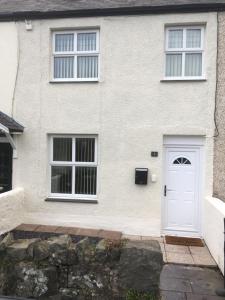a white house with a white door and windows at Snowdon Cottage in Caernarfon