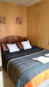 1 cama grande con 2 almohadas encima en Cabaña Don Claudio, en Osorno