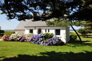 a small white house with flowers in front of it at Maison de vacances au bord de la plage in Trégunc